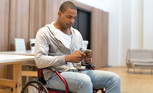person-i-rullstol-tittar-på- mobiltelefon