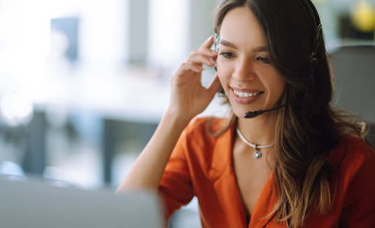 Mujer con auriculares hablando sobre Nuance Agent Coach