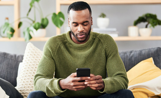 Sitzender Mann verwendet Smartphone Mann verwendet Smartphone und informiert sich über Voice-to-Digital-Lösungen