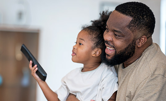 Dad and Daughter Speaking to TV Remote Dad and daughter using voice control Dragon TV